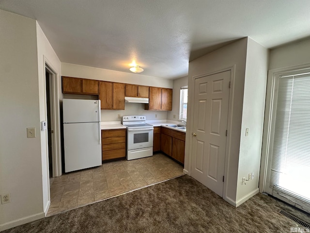 kitchen featuring white appliances, sink, light carpet, and a textured ceiling