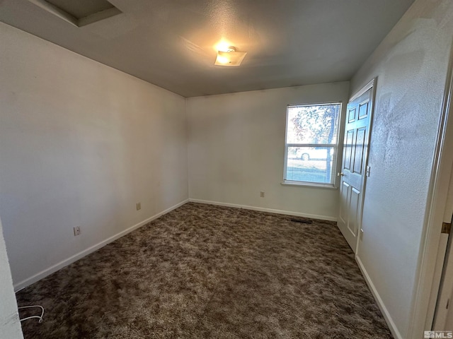 unfurnished room featuring dark colored carpet