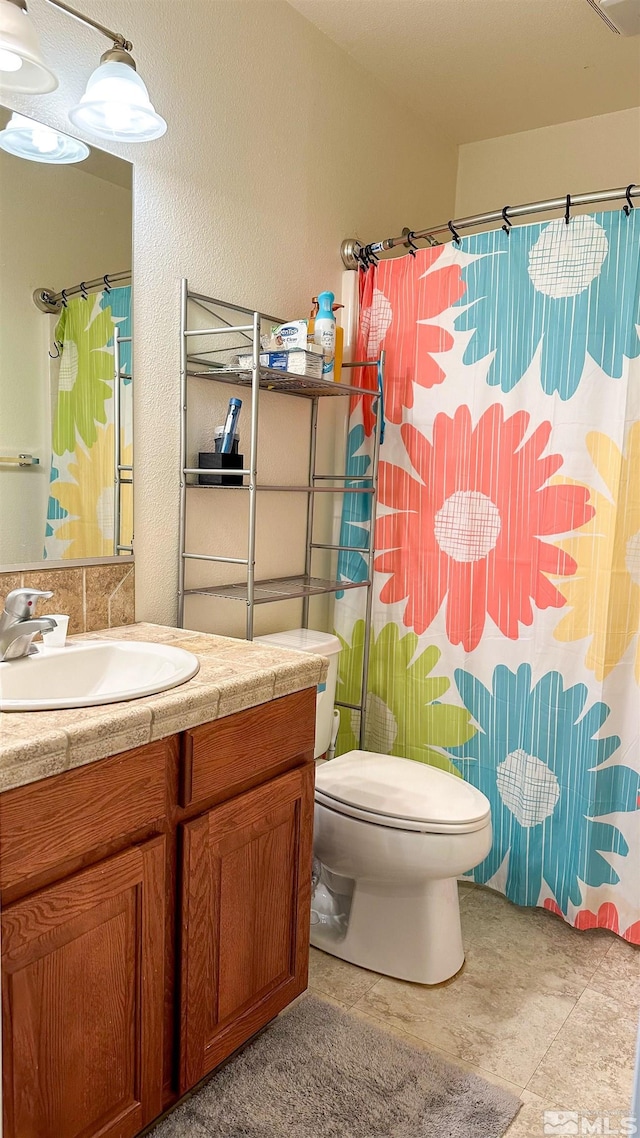 bathroom with a shower with curtain, vanity, toilet, and tile patterned floors