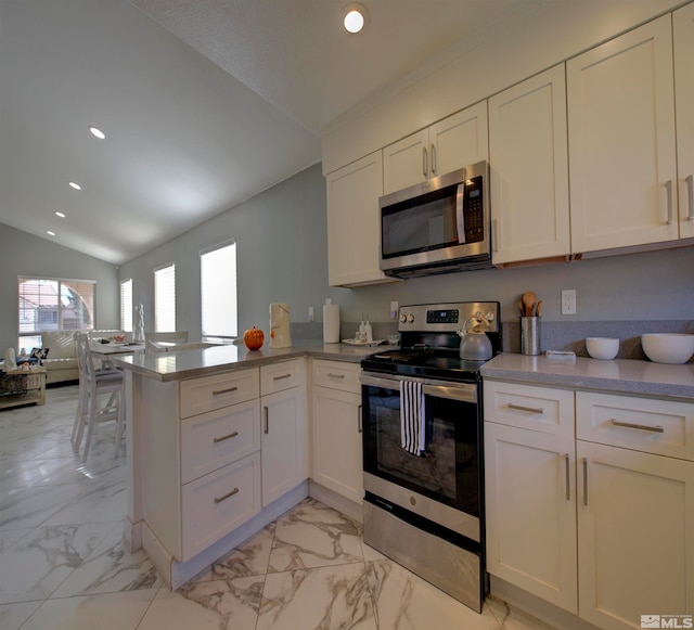 kitchen featuring kitchen peninsula, vaulted ceiling, white cabinets, and appliances with stainless steel finishes