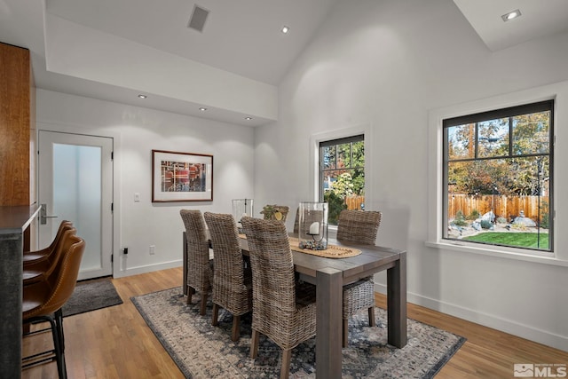 dining area featuring high vaulted ceiling and light hardwood / wood-style flooring