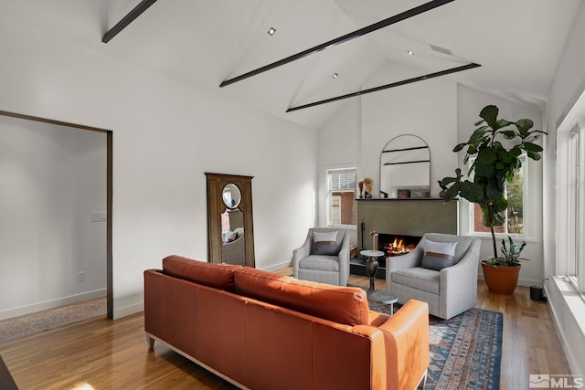 living room featuring beamed ceiling, light wood-type flooring, and high vaulted ceiling