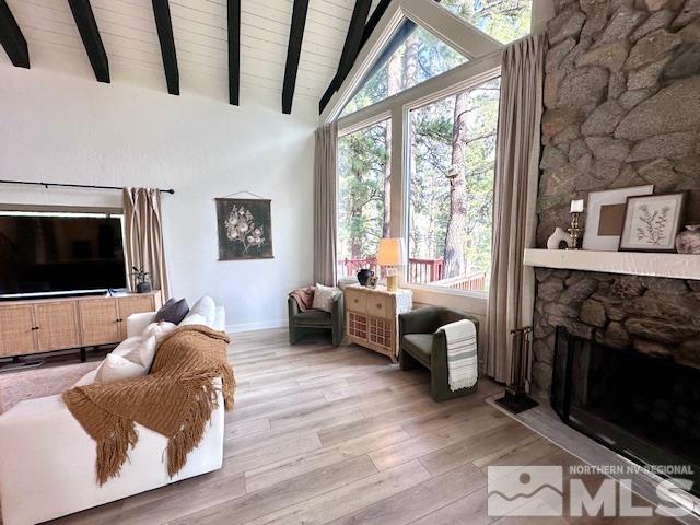 sitting room with a fireplace, vaulted ceiling with beams, and light hardwood / wood-style flooring