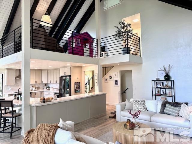 living room with high vaulted ceiling, beam ceiling, wooden ceiling, and light hardwood / wood-style flooring