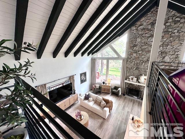 living room with hardwood / wood-style floors, a fireplace, beamed ceiling, and high vaulted ceiling