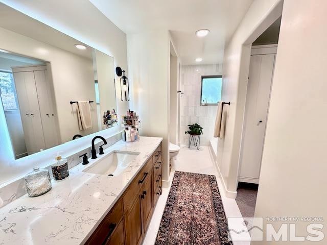 bathroom featuring toilet, vanity, tile patterned floors, and tiled shower