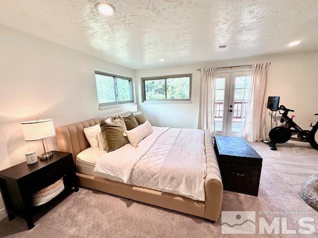bedroom featuring a textured ceiling, french doors, light colored carpet, and multiple windows