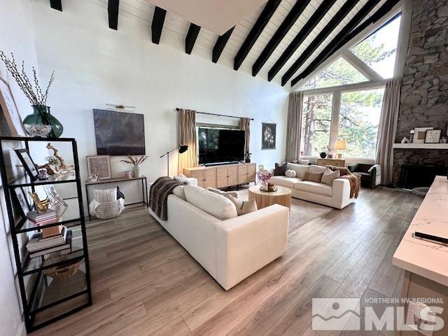 living room with high vaulted ceiling, beamed ceiling, hardwood / wood-style flooring, and a fireplace