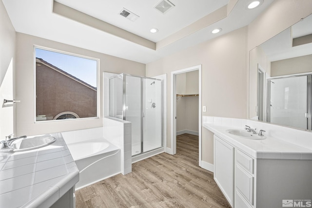 bathroom with hardwood / wood-style floors, vanity, and plus walk in shower