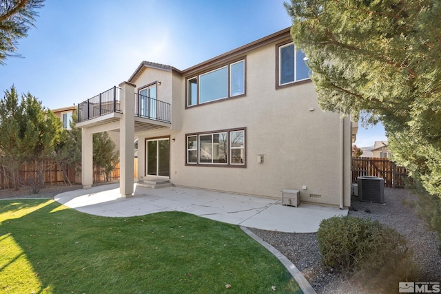 rear view of house featuring central air condition unit, a balcony, a yard, and a patio area