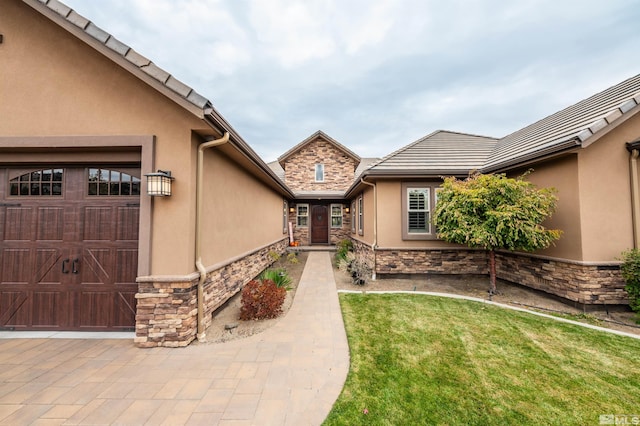 entrance to property featuring a lawn and a garage