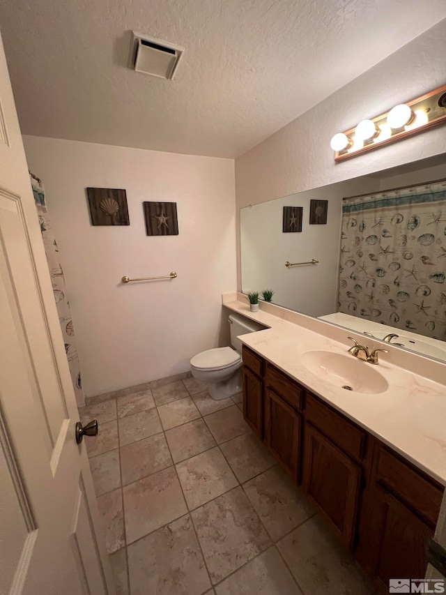 bathroom with tile patterned flooring, vanity, a textured ceiling, and toilet