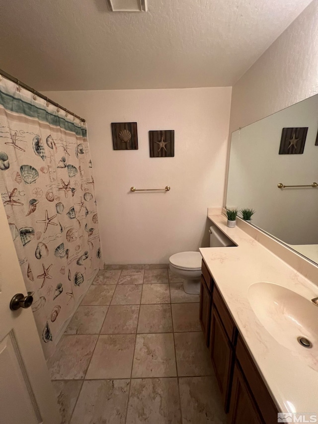 bathroom featuring tile patterned flooring, vanity, a textured ceiling, and toilet