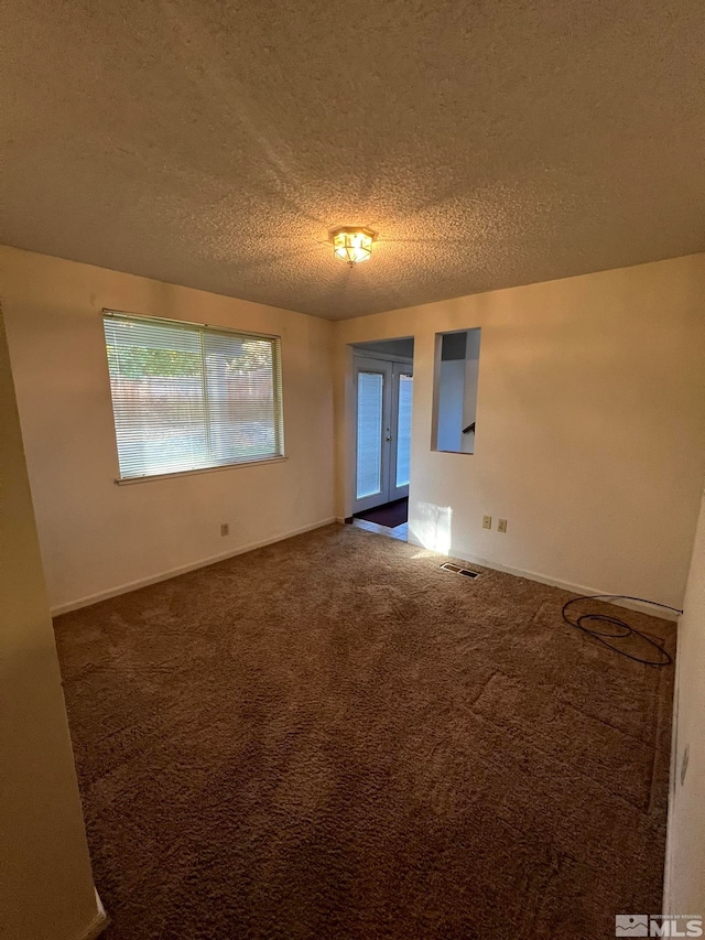 empty room featuring french doors, carpet, and a textured ceiling