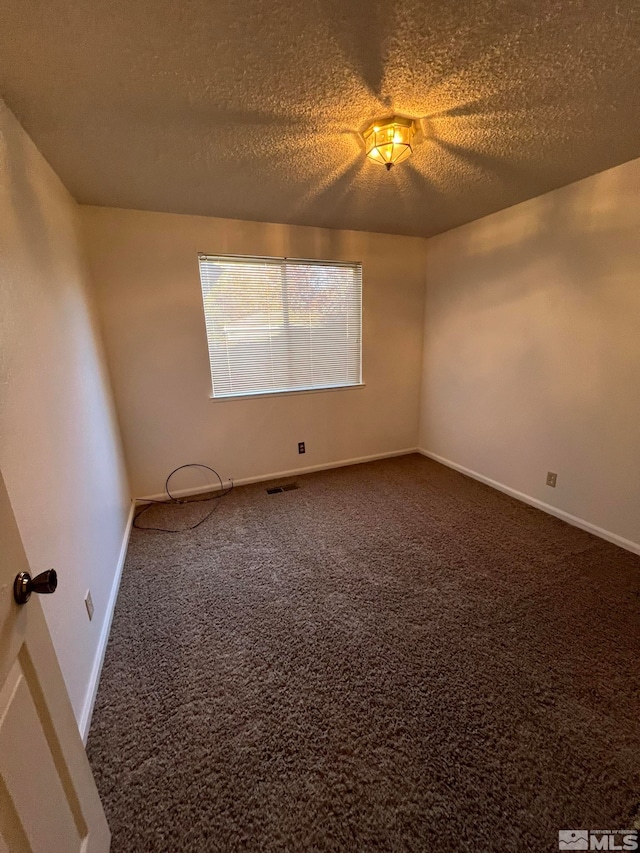 carpeted empty room featuring a textured ceiling