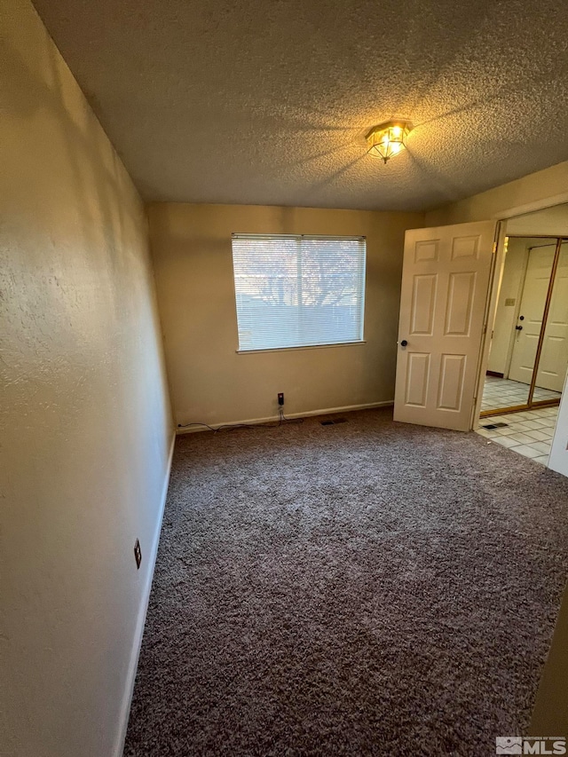 unfurnished room with carpet and a textured ceiling