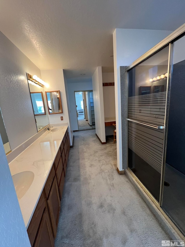 bathroom with a textured ceiling, vanity, and a shower with door