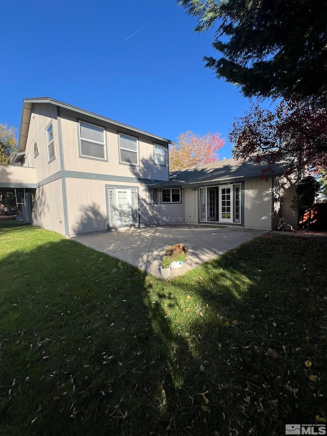 back of property with a yard and a patio