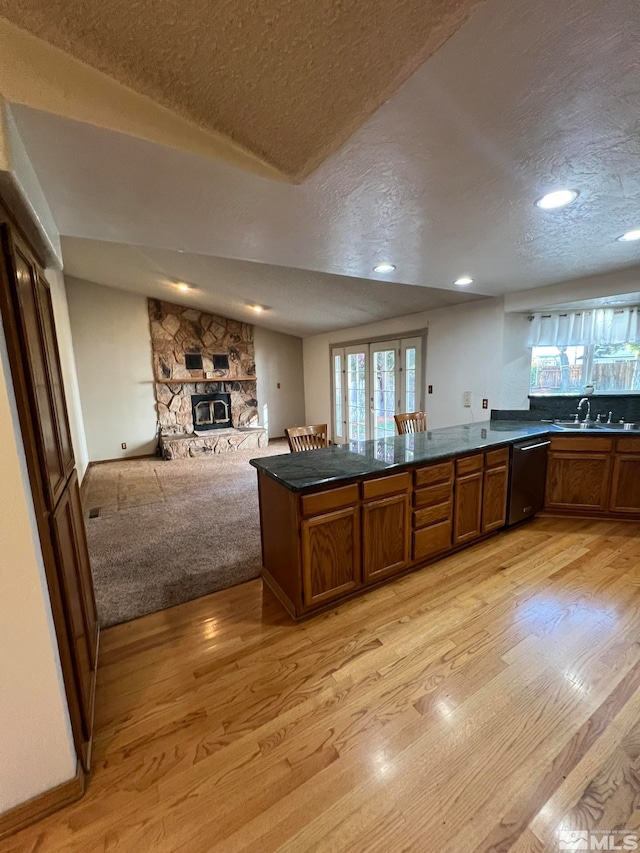 kitchen with dishwasher, sink, kitchen peninsula, light hardwood / wood-style floors, and a textured ceiling