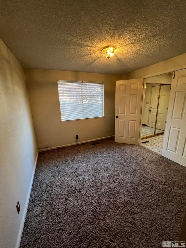 carpeted empty room featuring a textured ceiling