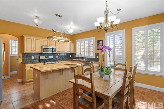 kitchen with stainless steel appliances, butcher block counters, sink, backsplash, and light brown cabinetry