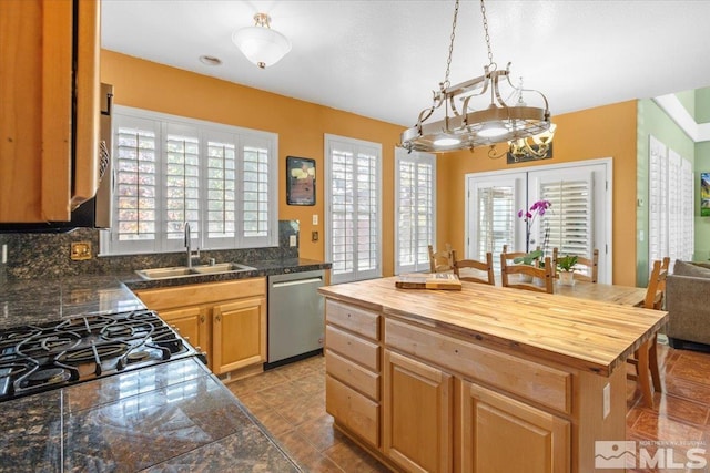 kitchen featuring stainless steel appliances, sink, backsplash, a kitchen island, and pendant lighting