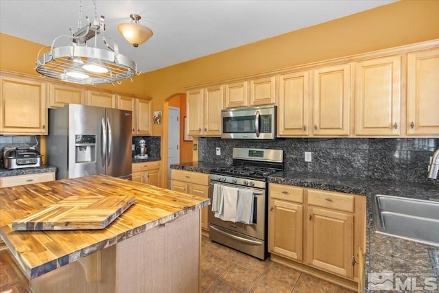 kitchen with stainless steel appliances, wood counters, sink, and backsplash