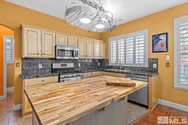 kitchen featuring tasteful backsplash, appliances with stainless steel finishes, wood counters, hanging light fixtures, and sink