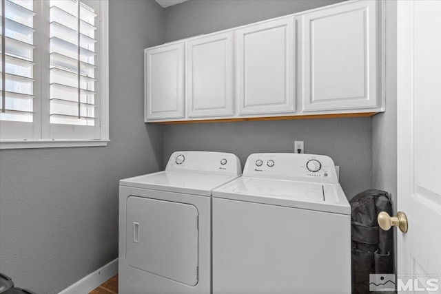 clothes washing area featuring cabinets and separate washer and dryer