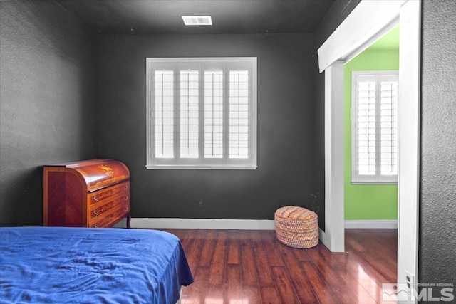 bedroom with multiple windows and dark hardwood / wood-style floors