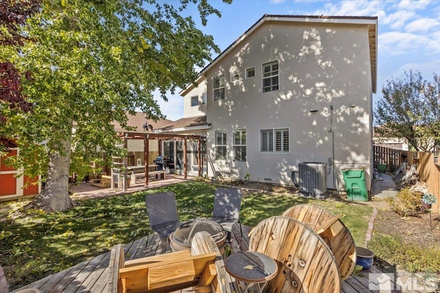 rear view of house featuring central AC unit, a wooden deck, and a fire pit