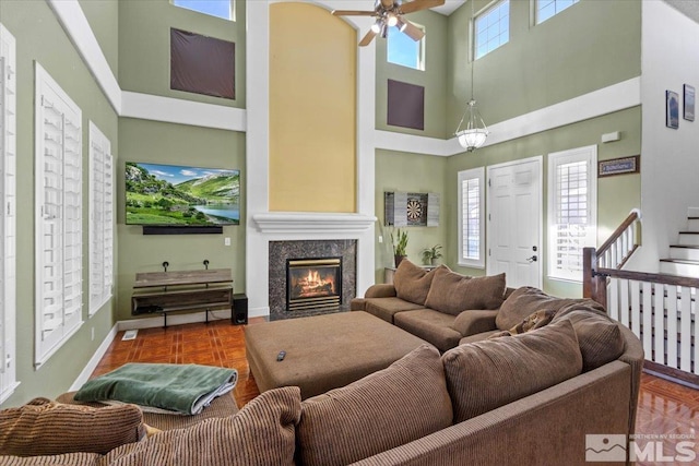 living room featuring a high ceiling, ceiling fan, and dark parquet floors