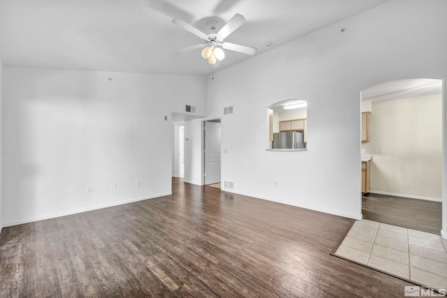 unfurnished living room featuring dark wood-type flooring, ceiling fan, and high vaulted ceiling