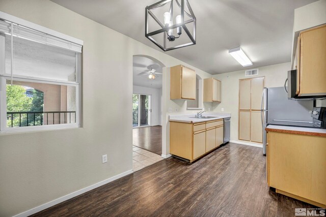 kitchen with appliances with stainless steel finishes, dark hardwood / wood-style flooring, hanging light fixtures, sink, and ceiling fan with notable chandelier