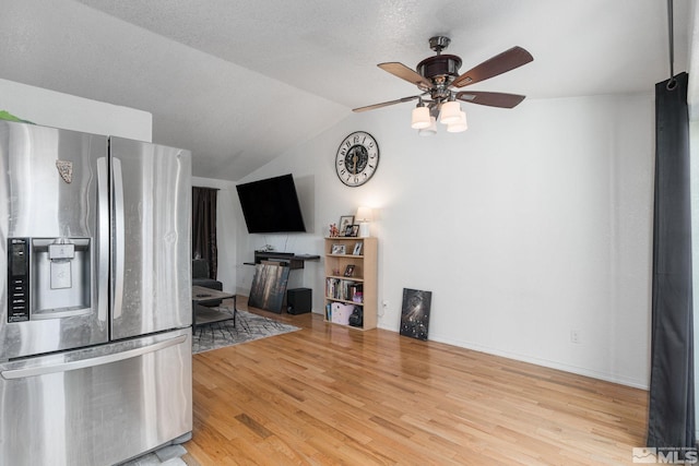 kitchen featuring stainless steel refrigerator with ice dispenser, ceiling fan, a textured ceiling, light wood-type flooring, and vaulted ceiling