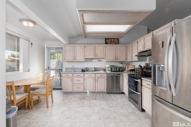 kitchen with light brown cabinets, appliances with stainless steel finishes, lofted ceiling, and sink