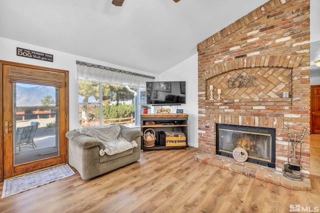 living room featuring hardwood / wood-style floors, lofted ceiling, and a brick fireplace