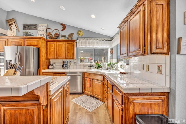 kitchen featuring tile countertops, lofted ceiling, and appliances with stainless steel finishes