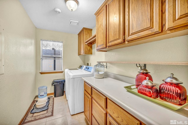 clothes washing area with cabinets, light tile patterned flooring, and washer and clothes dryer