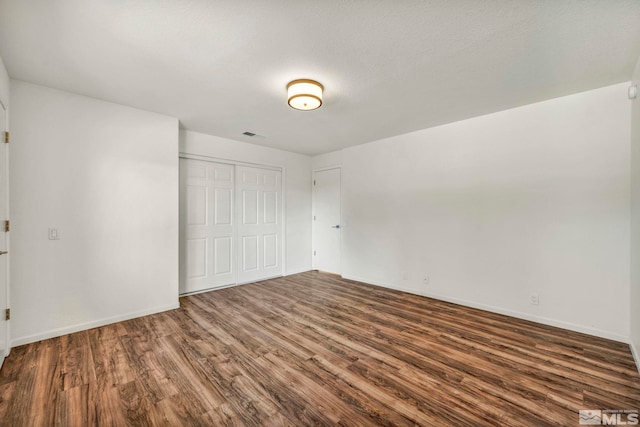 unfurnished bedroom with a textured ceiling, dark hardwood / wood-style floors, and a closet