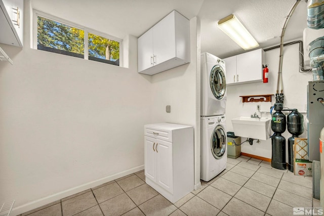 laundry room featuring cabinets, stacked washing maching and dryer, light tile patterned floors, and sink