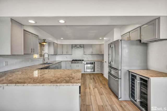 kitchen with gray cabinetry, wine cooler, light wood-type flooring, appliances with stainless steel finishes, and kitchen peninsula