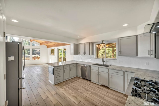 kitchen with decorative backsplash, light hardwood / wood-style flooring, sink, light stone countertops, and appliances with stainless steel finishes