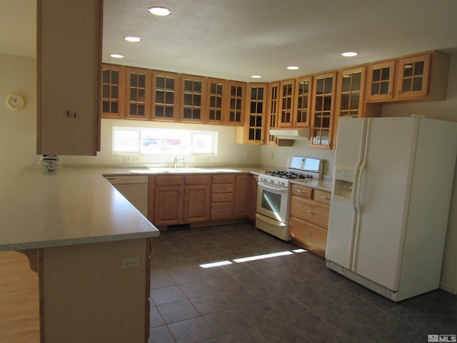 kitchen with sink, dark tile patterned floors, a breakfast bar, kitchen peninsula, and white appliances