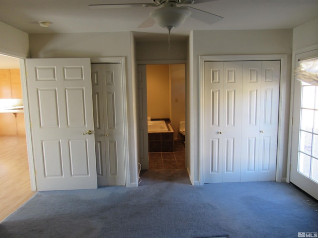 unfurnished bedroom with ensuite bath, two closets, ceiling fan, and carpet floors