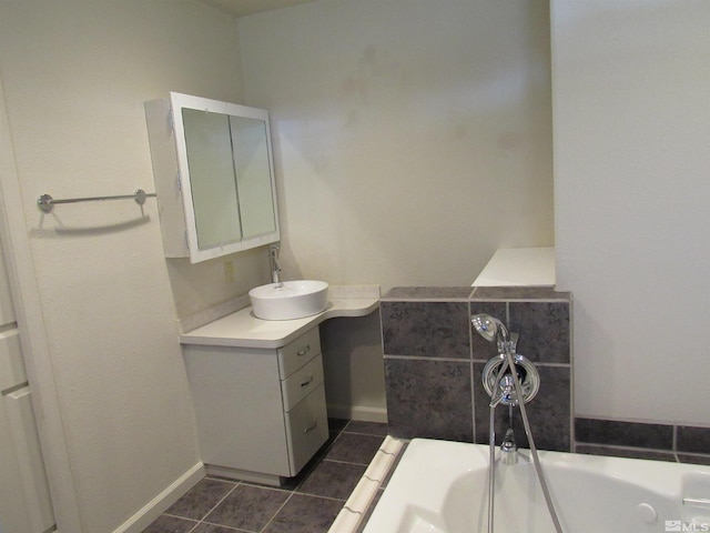 bathroom with a tub to relax in, vanity, and tile patterned floors