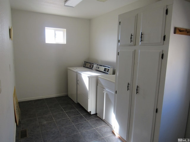 washroom featuring dark tile patterned floors, cabinets, and washer and dryer