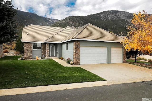 ranch-style home featuring a mountain view, a front yard, and a garage