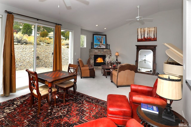 carpeted living room with vaulted ceiling, a stone fireplace, and ceiling fan