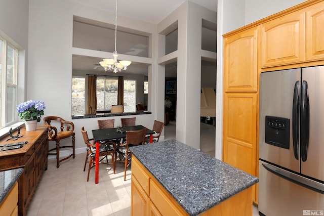 kitchen with stainless steel refrigerator with ice dispenser, built in shelves, decorative light fixtures, an inviting chandelier, and a center island